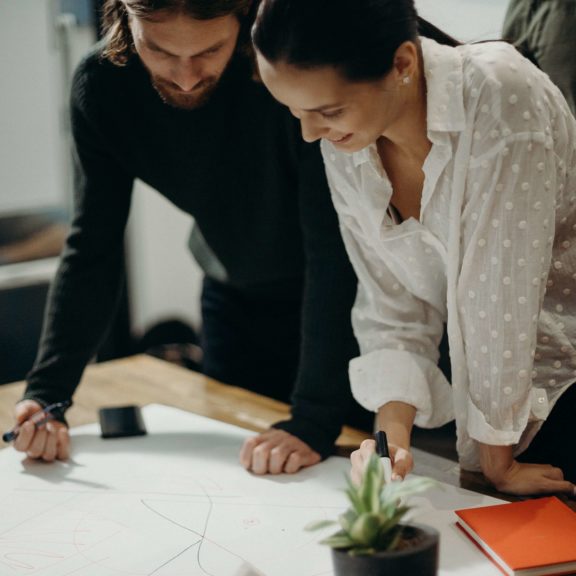 man-and-woman-leaning-on-table-staring-at-white-board-on-top-3205570 (1)