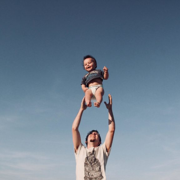 photo-of-man-in-raising-baby-under-blue-sky-1166990